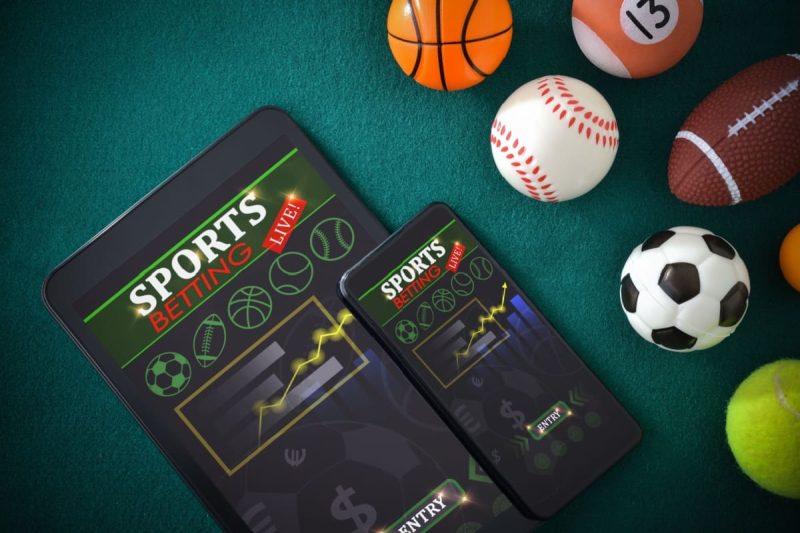 telefon si tableta afisand pariuri sportive si diverse mingi specifice sporturilor in jur