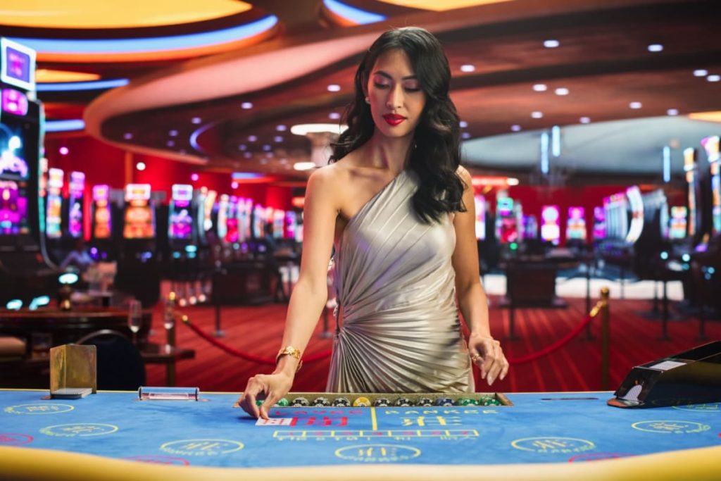 femeie crupier asezand cartile pe o masa de baccarat live online