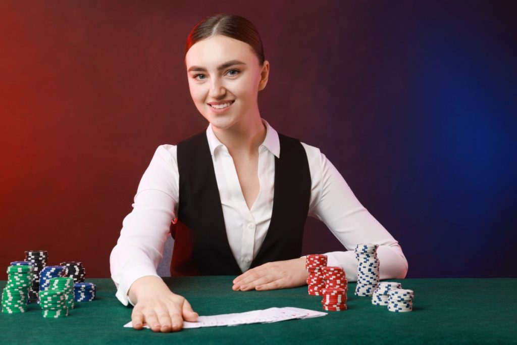 dealer cu carti de joc si jetoane in fata unei mese de baccarat online live