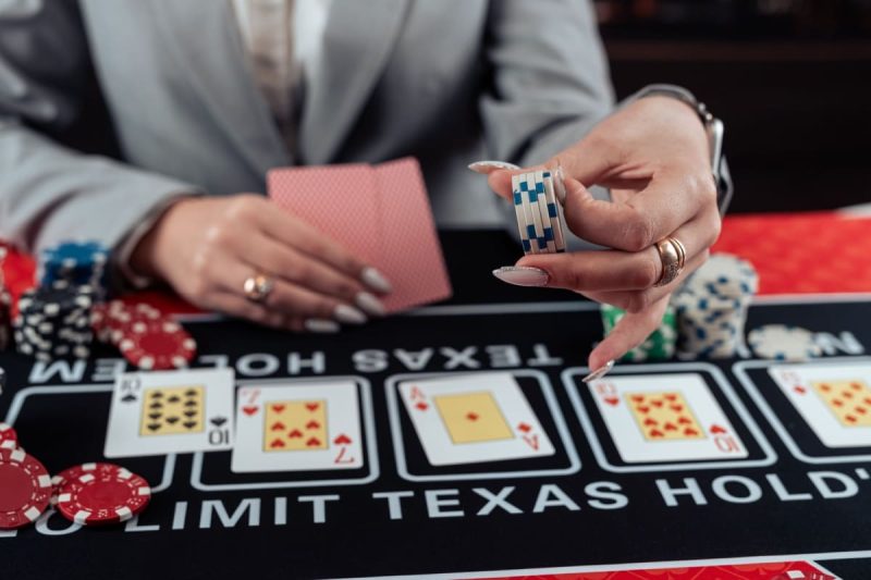 jucatoare de poker cu carti de joc si jetoane in mana marind miza intr-o runda
