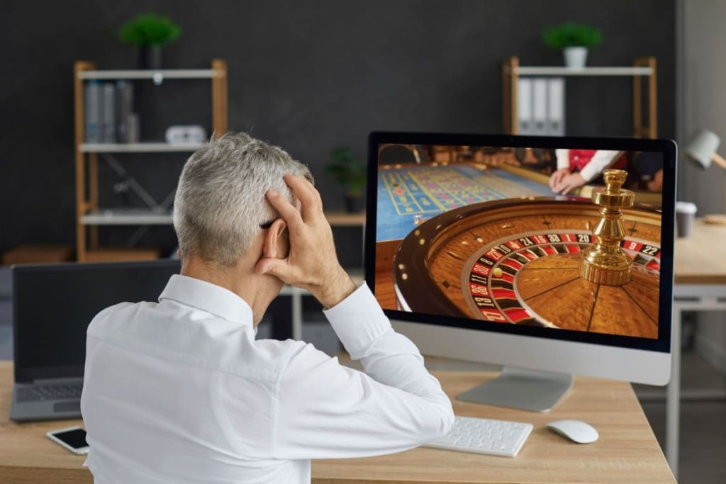 barbat stresat urmarind o runda de ruleta online pe laptop