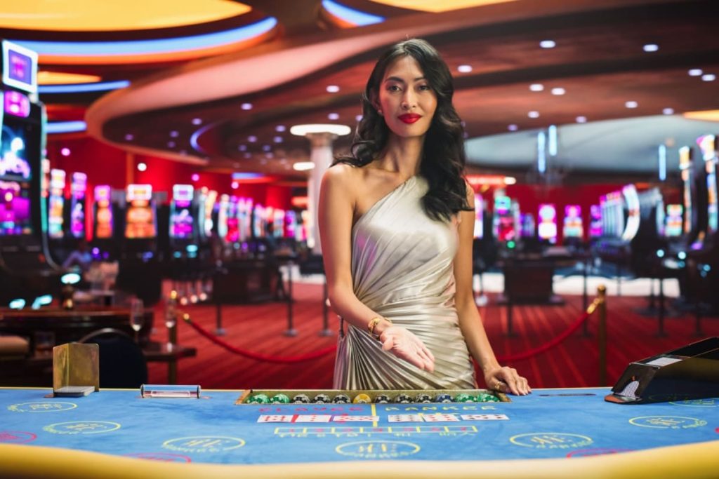 femeie crupier invitand privitorul la o masa de baccarat live online
