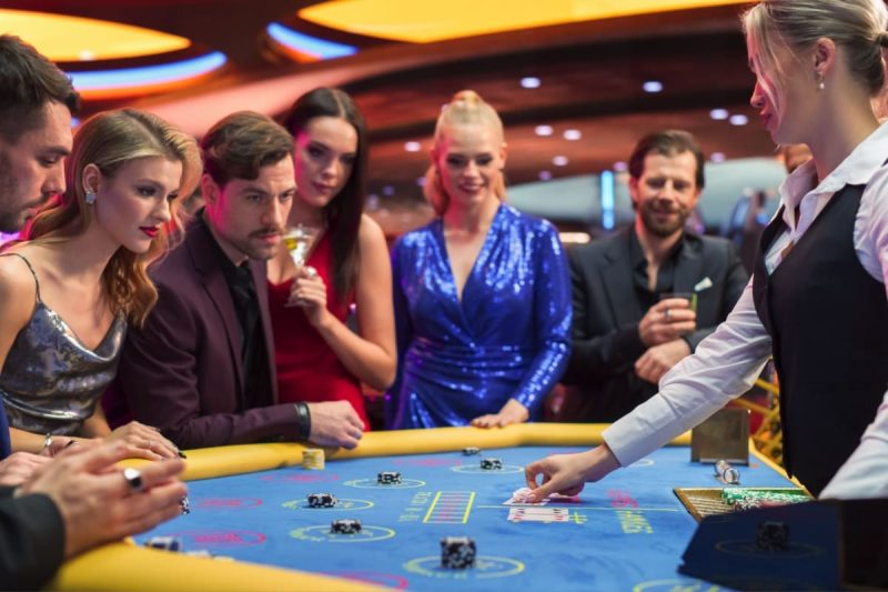 crupier si jucatori in jurul unei mese de baccarat dintr-un casino