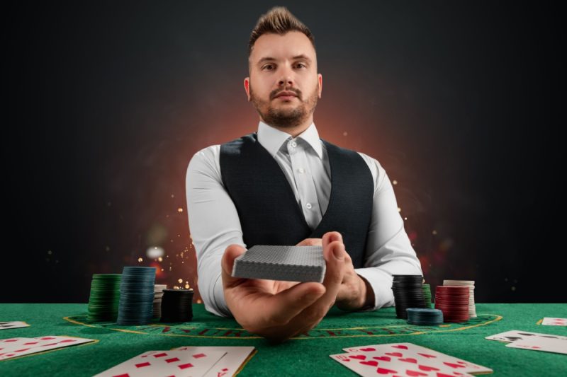 dealer cu un pachet de carti de joc in mana intr-un studio de balackjack online live casino