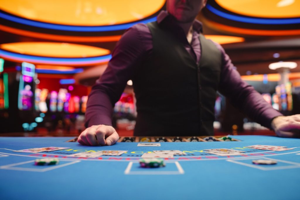 dealer tragand o carte la o masa de blackjack intr-un cazino