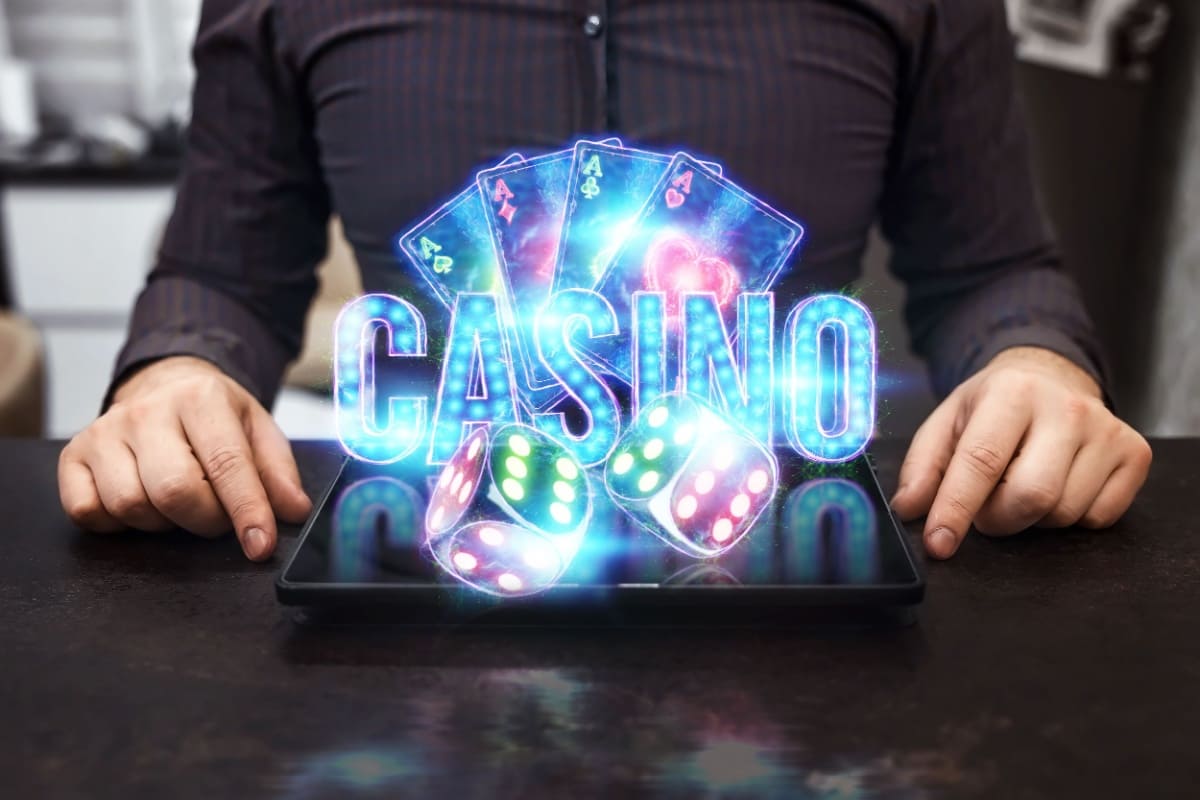 barbat cu o tableta in fata din care se ridica elemente specifice jocurilor de casino in culori neon