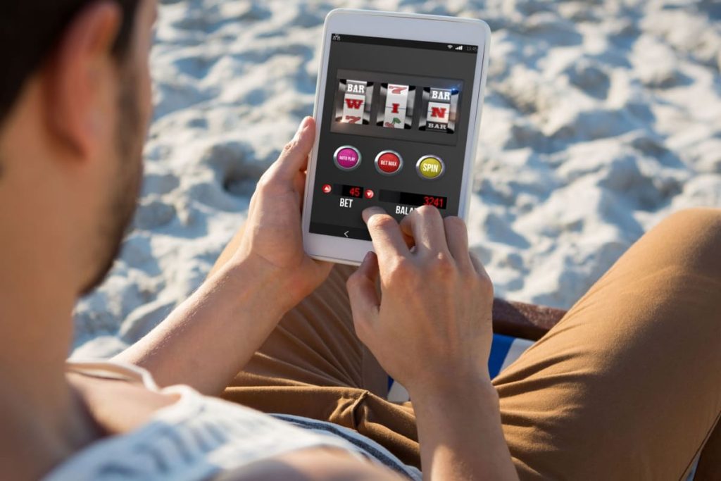 barbat jucand un slot de casino online pe telefonul mobil pe plaja