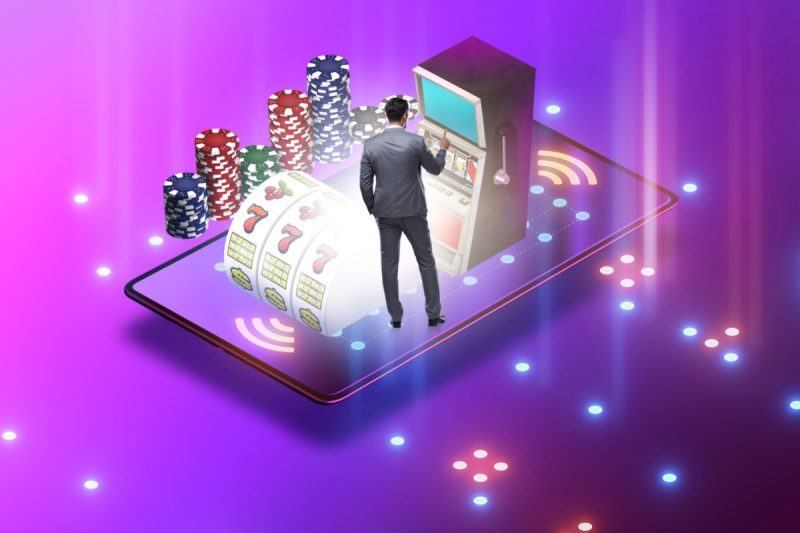 ilustratie cu un barbat si un telefon mobil, alaturi de un aparat de slot si jetoane de cazino