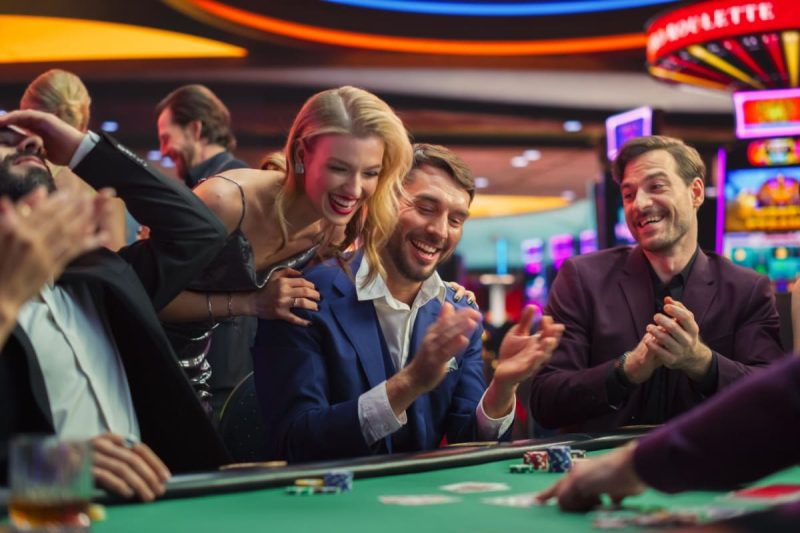 grup de jucatori fericiti asezati la o masa de casino