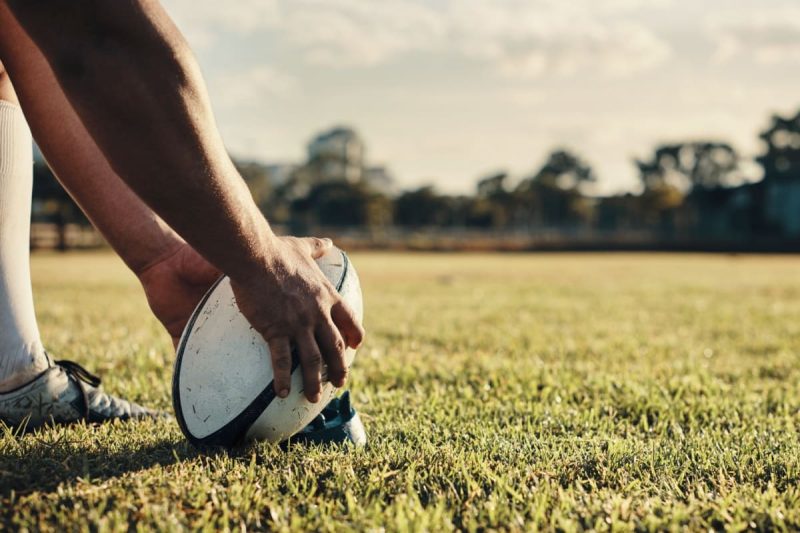 jucator de rugby plaseaza mingea pe suport inaintea unui sut