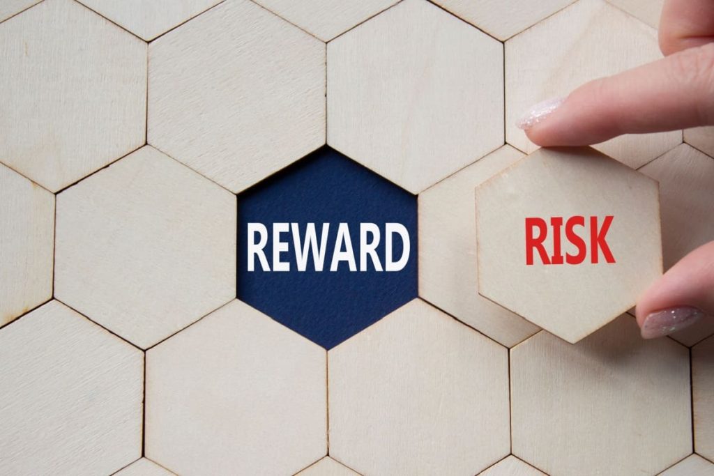 puzzle cu o mana ridicand o piesa pe care scrie RISK, sub ea aflandu-se scris REWARD
