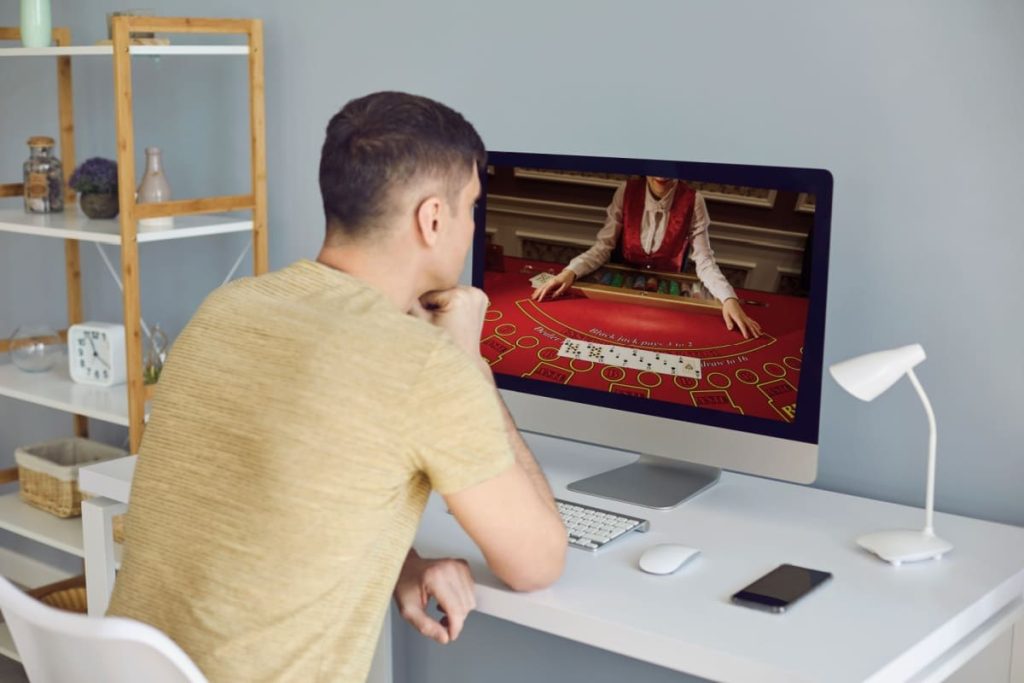 barbat urmarind atent un joc de blackjack live online pe ecranul computerului