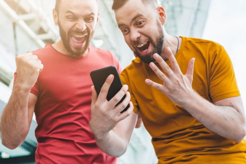 doi barbati entuziasmati, uitandu-se la un telefon mobil