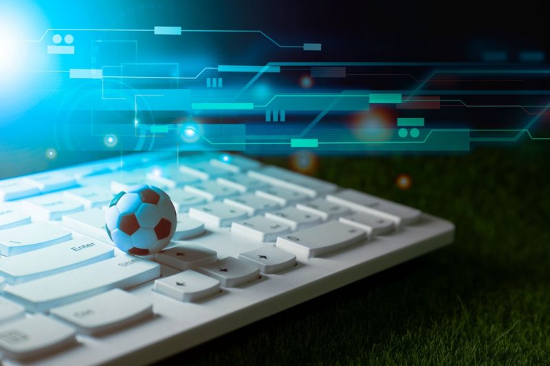 o mica minge de fotbal pe o tastatura, cu grafice in fundal