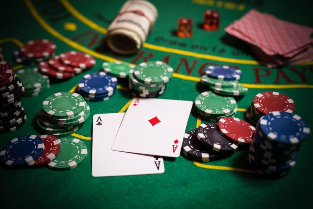 carti de joc si jetoane pe o masa de blackjack dintr-un cazino fizic, cu o pereche As-As in prim plan