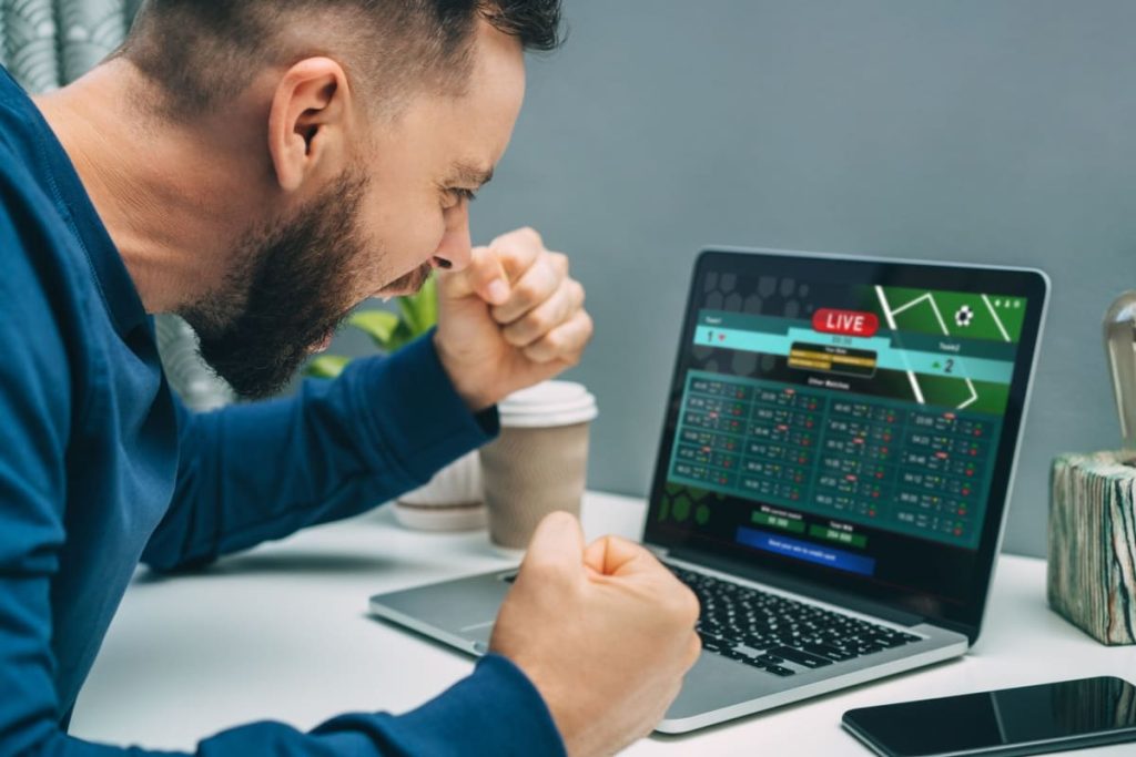 barbat entuziasmat, urmarind pe laptop statisticile live ale unui meci de fotbal
