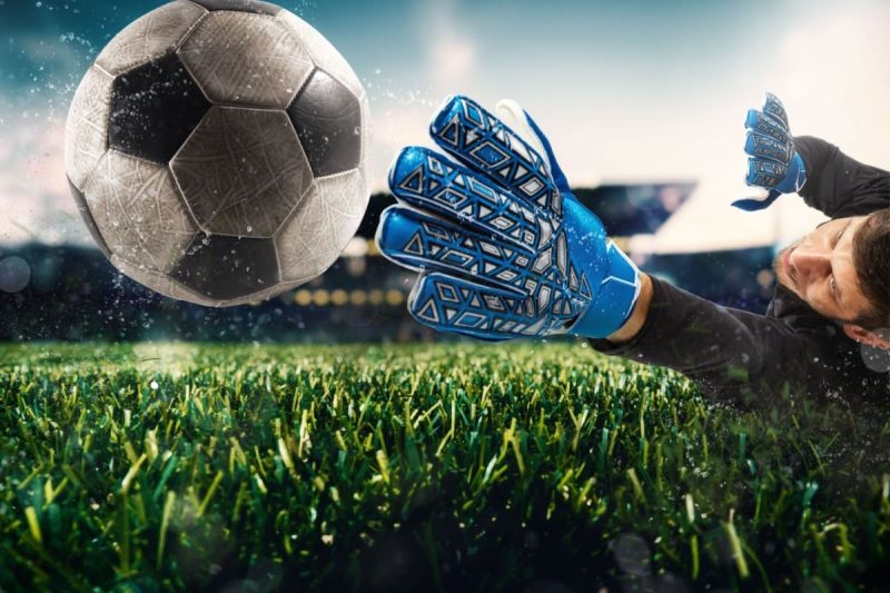 portar in timpul unui meci de fotbal intinzandu-se dupa minge