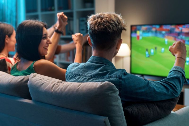 grup de prieteni fericiti urmarind un meci de fotbal la televizor