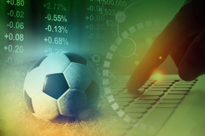 minge de fotbal, alaturi de un laptop, cu statistici si cote in fundal