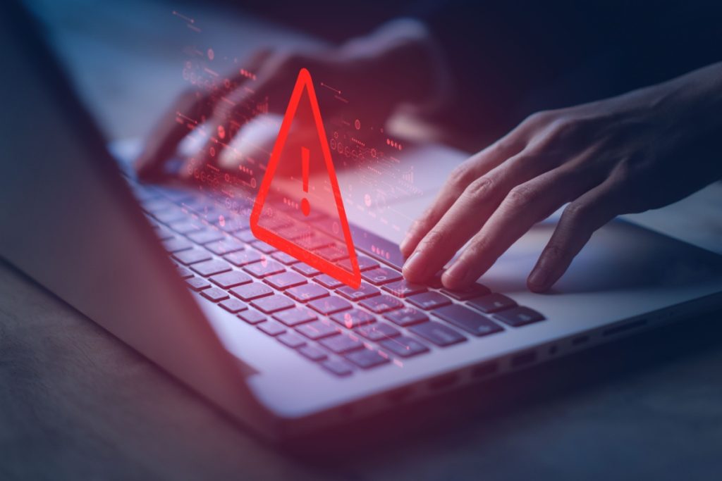 persoana in fata unui laptop, cu elemente grafice de atentionare