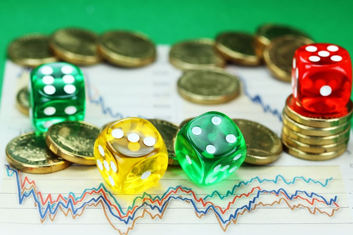 monede si zaruri asezate pe o foaie cu graficele cheltuielilor lunare