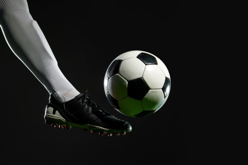 jucator de fotbal care tine mingea pe picior