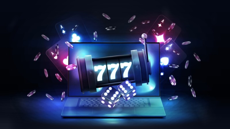 laptop, slot care afiseaza 777, zaruri, jetoane si carti de joc pe fundal