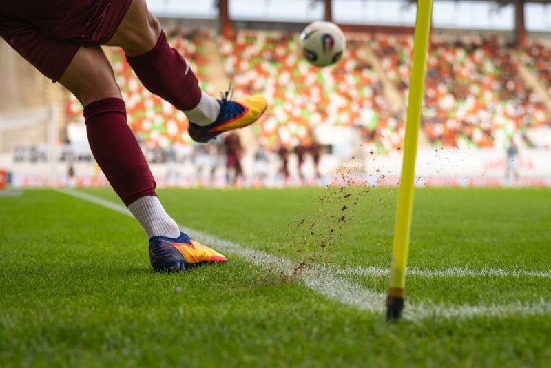 jucator de fotbal care șutează mingea din coltul careului