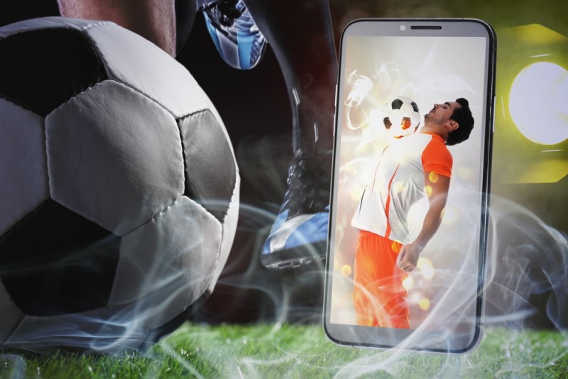 minge de fotbal pe teren si telefon mobil pentru pariuri sportive