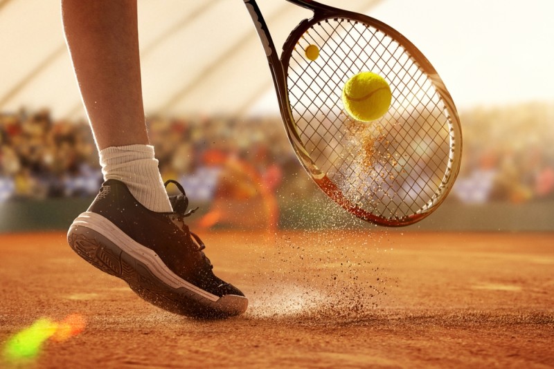 Jucator de tenis performand pe terenul de zgura de la Roland Garros